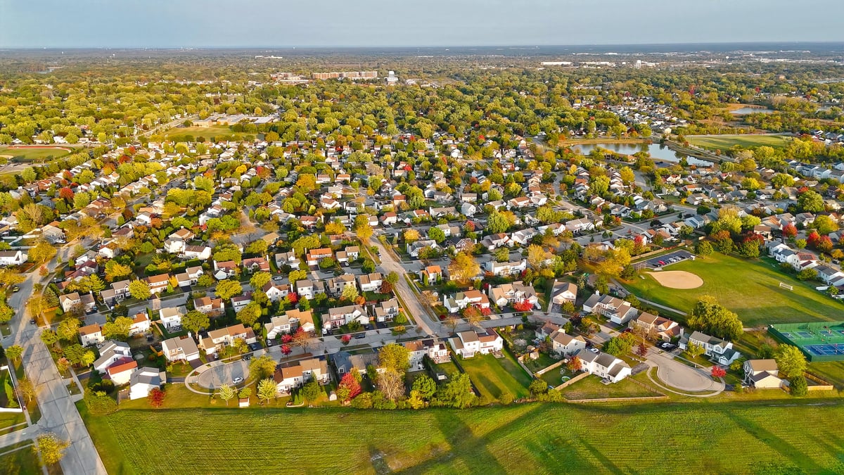 Wide aerial view of suburban community with houses and tree-lined streets