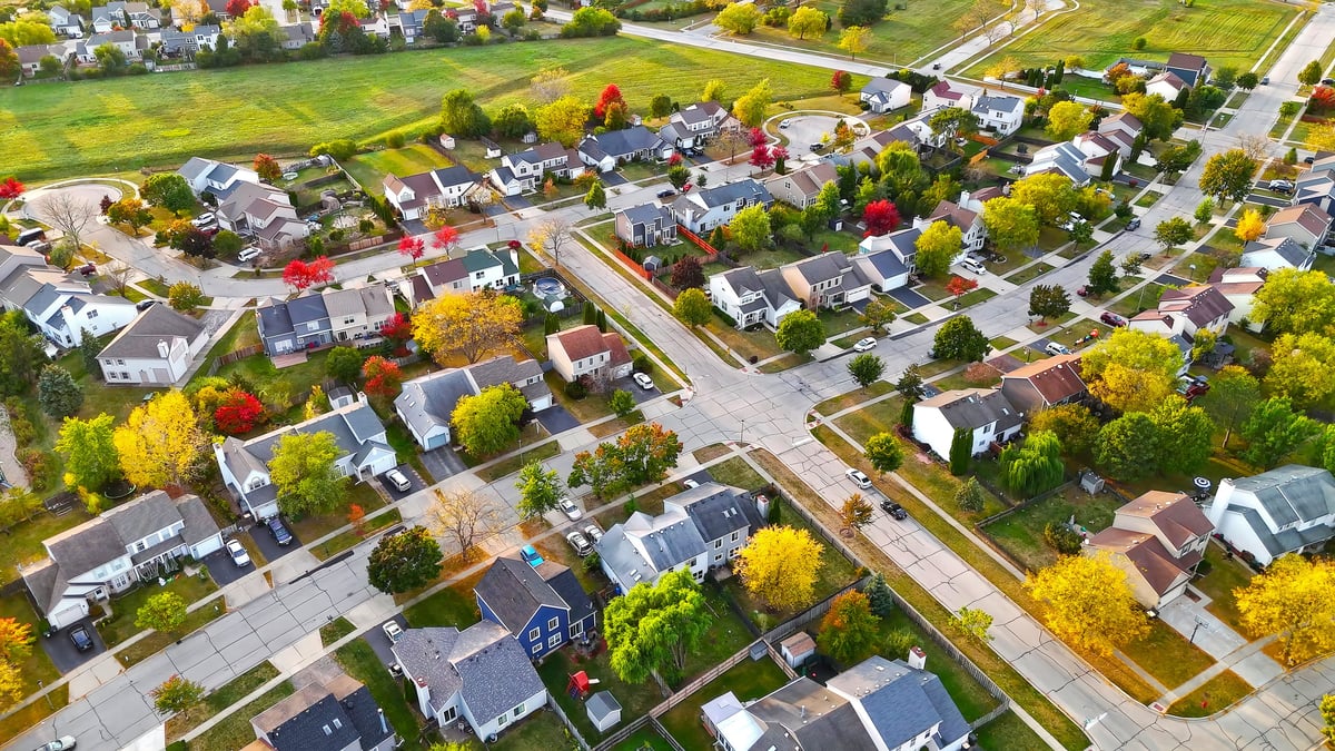 Aerial view of suburban neighborhood in autumn with colorful trees and green spaces
