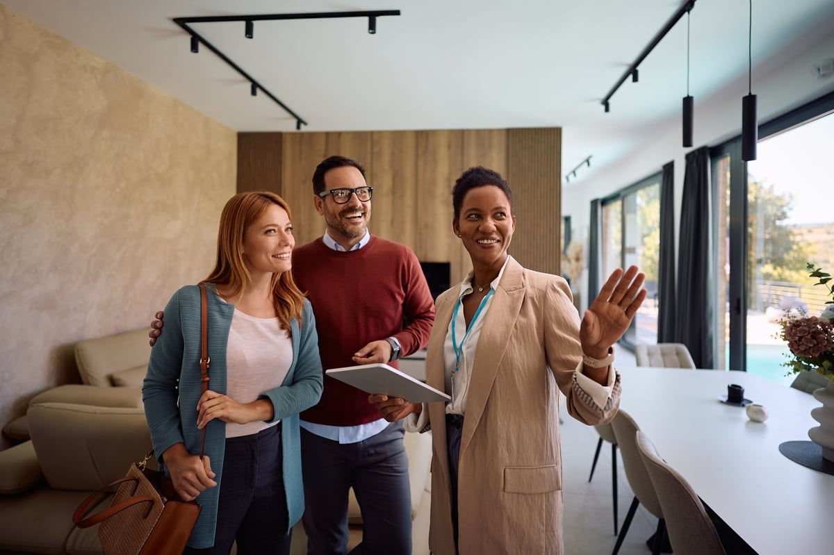 Happy real estate agent showing new house to couple