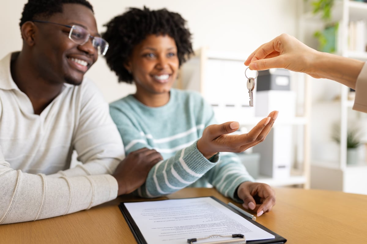 Excited couple receiving house keys from real estate agent