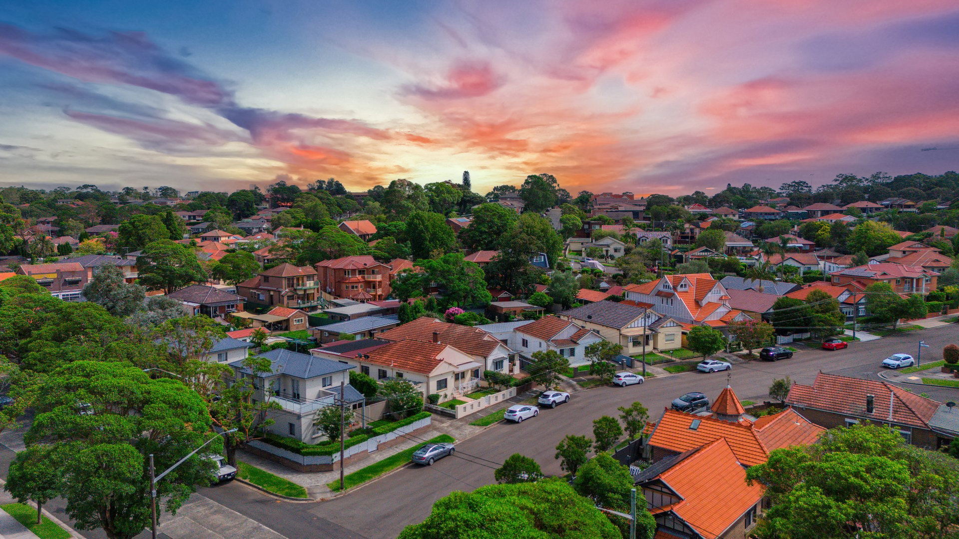 Aerial drone view of suburban homes, streets, parks, and trees